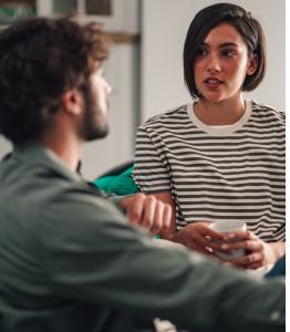 Two young adults engaged in a supportive conversation in their living room